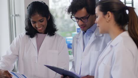 International-Group-of-Scientists-in-Laboratory.science-research,-work-and-people-concept-international-group-of-happy-scientists-with-clipboards-discussing-report-in-laboratory