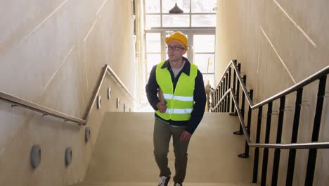 Builder-in-Helmet-with-Clipboard-Walking-Upstairs.architecture,-construction-and-building-concept-male-builder-in-helmet-and-safety-west-with-clipboard-walking-upstairs