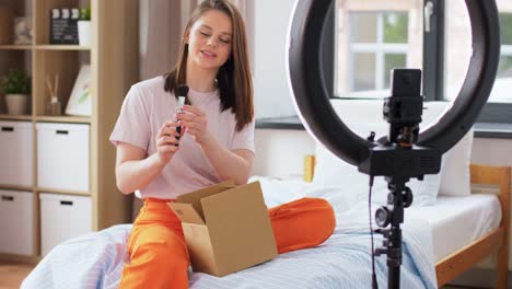 Glückliches-Blogger-Mädchen-Packt-Paketkasten-Zu-Hause-Aus.-Bloggen,-Technologie-Und-People-Konzept-Glückliches-Lächelndes-Mädchen-Oder-Beauty-Bloggerin-Mit-Ringlicht-Und-Smartphone-Packt-Paketkasten-Mit-Kosmetik-Zu-Hause-Aus