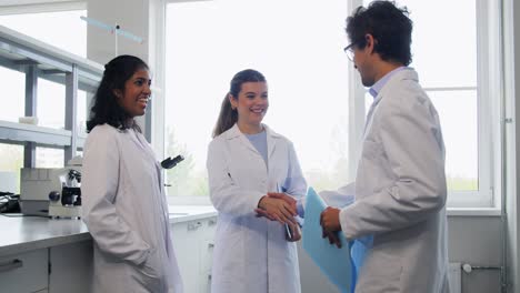 Scientists-Shaking-Hands-in-Laboratory.science,-work-and-people-concept-international-group-of-happy-scientists-shaking-hands-in-laboratory