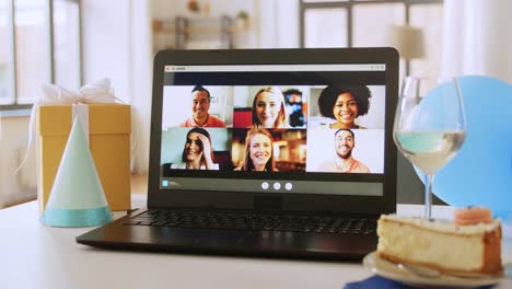 Computadora-Portátil-Con-Familia-Teniendo-Una-Fiesta-De-Cumpleaños-Virtual.-Concepto-De-Personas,-Tecnología-Y-Comunicación-En-Línea-Computadora-Portátil-Con-Una-Familia-Teniendo-Una-Videollamada-O-Una-Fiesta-De-Cumpleaños-Virtual-En-La-Pantalla,-Pastel,-Caja-De-Regalo-Y-Café-En-La-Mesa-En-Casa