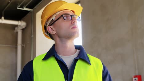 Builder-in-Helmet-and-Safety-West-with-Tablet-Pc.architecture,-construction-business-and-building-concept-male-builder-in-helmet-and-safety-west-with-tablet-pc-computer-at-office