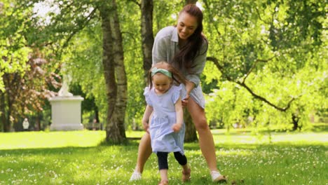 Madre-Feliz-Con-Una-Hija-Pequeña-Jugando-En-El-Parque.-Concepto-De-Familia,-Maternidad-Y-Personas-Madre-Feliz-Con-Una-Hija-Pequeña-Jugando-En-El-Parque-O-Jardín-De-Verano