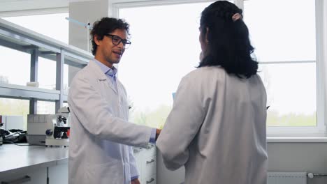 Scientists-Shaking-Hands-in-Laboratory.science,-work-and-people-concept-international-group-of-happy-scientists-shaking-hands-in-laboratory