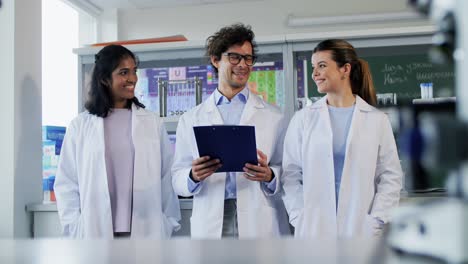 International-Group-of-Scientists-in-Laboratory.science-research,-work-and-people-concept-international-group-of-happy-scientists-with-clipboards-discussing-report-in-laboratory