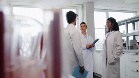 International-Group-of-Scientists-in-Laboratory.science-research,-work-and-people-concept-international-group-of-happy-scientists-with-clipboards-discussing-report-in-laboratory