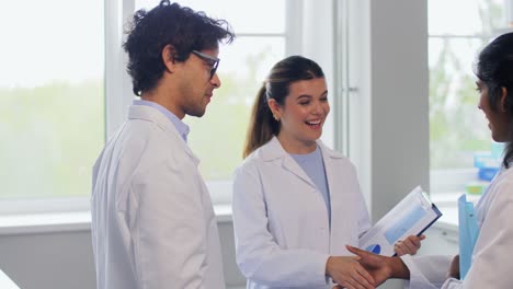 Scientists-Shaking-Hands-in-Laboratory.science,-work-and-people-concept-international-group-of-happy-scientists-shaking-hands-in-laboratory