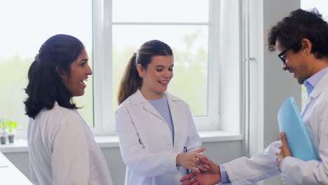 Scientists-Shaking-Hands-in-Laboratory.science,-work-and-people-concept-international-group-of-happy-scientists-shaking-hands-in-laboratory