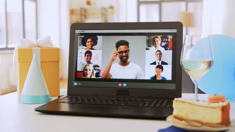 Laptop-with-Family-Having-Virtual-Birthday-Party.people,-technology-and-online-communication-concept-laptop-with-family-having-video-call-or-virtual-birthday-party-on-screen,-cake,-gift-box-and-coffee-on-table-at-home