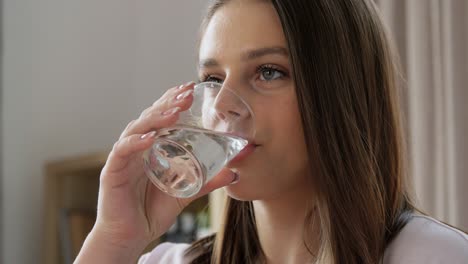 Mädchen-Mit-Einem-Glas-Wasser-Sitzt-Zu-Hause-Auf-Dem-Bett.-Menschenkonzept-Glücklich-Lächelndes-Mädchen-Mit-Einem-Glas-Wasser-Sitzt-Zu-Hause-Auf-Dem-Bett