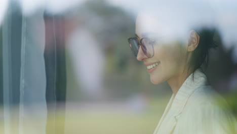 View-of-Thoughtful-Woman-Writing-in-Notebook-Through-Window