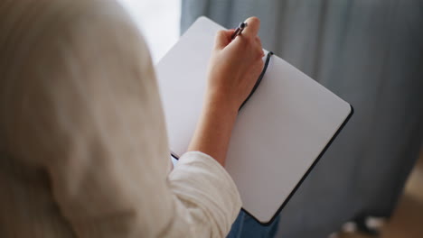 Close-Up-of-Businesswoman's-Hands-Writing-in-Notebook