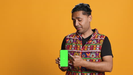 Influencer-presenting-green-screen-phone,-isolated-over-studio-background