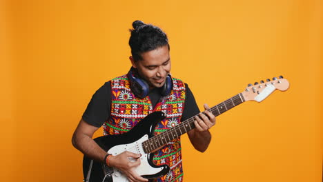 Happy-man-holding-electric-guitar,-playing-rock-music,-studio-background