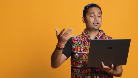 Man-with-friends-in-teleconference-meeting-using-laptop,-studio-background