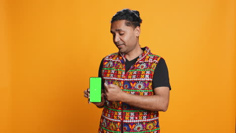 Influencer-presenting-green-screen-phone,-isolated-over-studio-background
