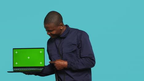 Portrait-of-happy-security-guard-at-work-showcasing-green-screen-laptop