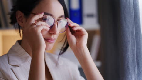 Una-Mujer-Pensativa-Se-Pone-Gafas-Y-Piensa-Junto-A-La-Ventana