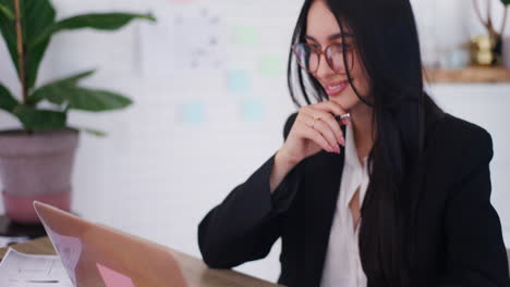 Happy-Businesswoman-Writing-on-Laptop-in-Office