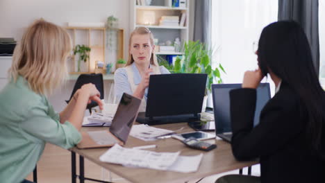 Three-Female-Employees-Discuss-Project-During-Meeting