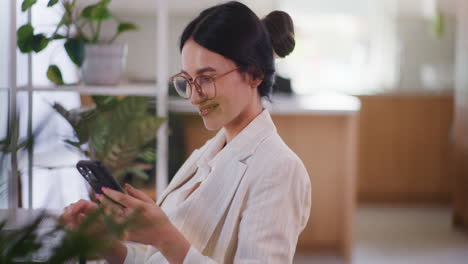 Mujer-Feliz-Desplazándose-Por-El-Teléfono-Inteligente-Y-Trabajando-En-La-Computadora-Portátil