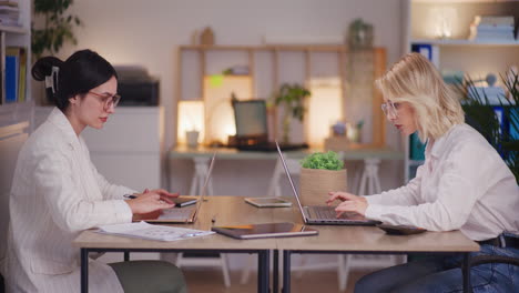 Woman-Worried-on-Laptop-While-Teammate-Enjoys