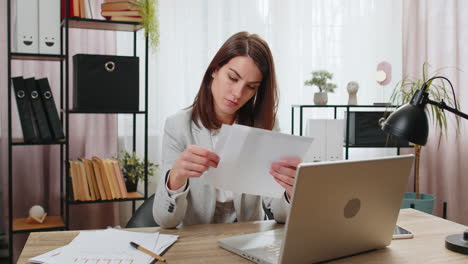 Businesswoman-girl-opening-envelope-reading-bad-news-in-letter-feels-upset-bankruptcy-at-home-office