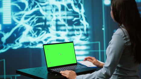 Startup-employee-looking-over-charts,-using-AI-software-on-green-screen-laptop