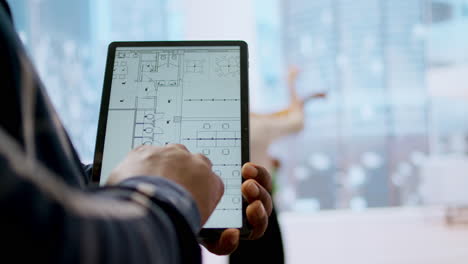 Financier-realtor-and-client-examining-blueprints-on-a-tablet