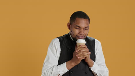 Cheerful-waiter-drinking-a-cup-of-coffee-and-relaxing-after-serving-clients