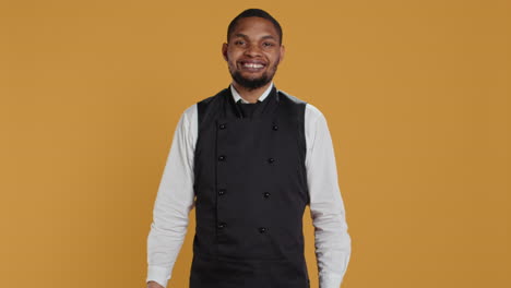 Restaurant-staff-showing-tablet-with-green-screen-against-yellow-background