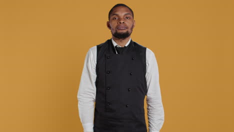 Waiter-in-uniform-showing-a-stop-sign-with-his-palm-raised-in-studio