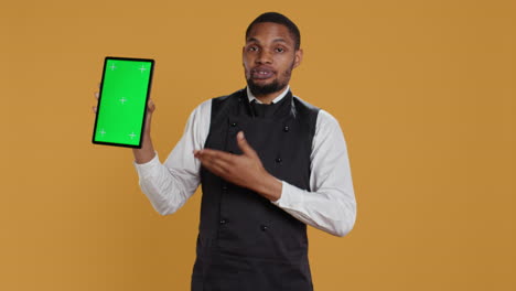 Restaurant-waiter-presenting-a-green-screen-layout-on-tablet