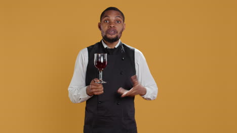 Waiter-offering-a-glass-of-wine-to-customers-waiting-for-food-at-the-table