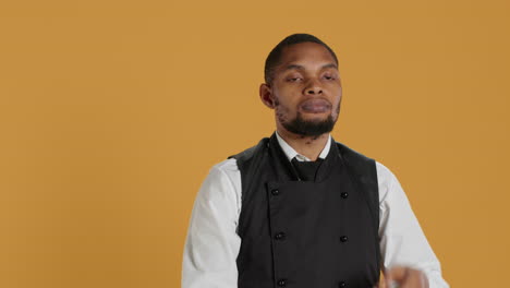 Waiter-in-uniform-showing-a-stop-sign-with-his-palm-raised-in-studio