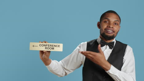 Hospitality-industry-personnel-showing-wall-sign-pointer-to-the-conference-room