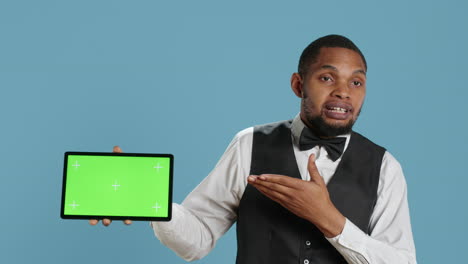 Doorkeeper-bellboy-poses-with-green-screen-on-tablet-at-the-hotel-reception