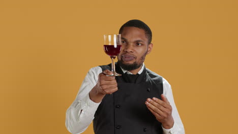 Waiter-offering-a-glass-of-wine-to-customers-waiting-for-food-at-the-table