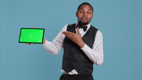 Doorkeeper-bellboy-poses-with-green-screen-on-tablet-at-the-hotel-reception