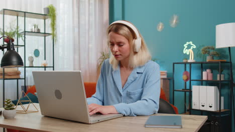 Happy-relaxed-businesswoman-sitting-at-home-office-listening-to-favorite-energetic-disco-music