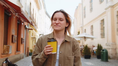 Mujer-Sonriente-Caminando-Por-Las-Calles-De-La-Ciudad-Disfrutando-Del-Café-De-La-Mañana-Café-Caliente-Relajándose-Tomando-Un-Descanso