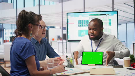 Financial-advisor-works-with-a-green-screen-at-table-with-his-senior-clients