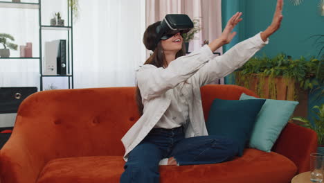 Una-Mujer-Joven-Usa-Gafas-De-Realidad-Virtual-En-Casa,-Disfrutando-Del-Concepto-De-Vídeo-Moviendo-Las-Manos-En-El-Aire