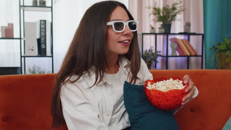 Woman-sitting-on-couch-eating-popcorn-and-watching-interesting-TV-serial,-sport-game-online-at-home