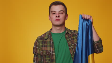 Young-man-holding-Ukraine-national-flag,-showing-victory-sign-against-war-hoping-for-success-and-win