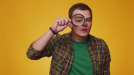 Investigator-researcher-man-with-magnifying-glass-near-face,-looking-into-camera-with-big-zoom-eye