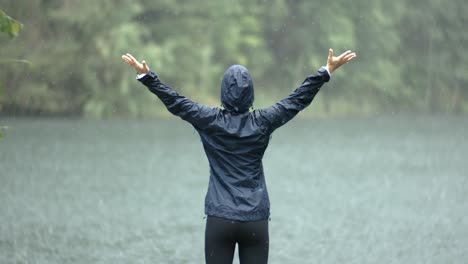 Frau-Steht-Im-Strömenden-Regen-Vor-Dem-Hintergrund-Eines-Sees.-Aufgenommen-Mit-Super-Zeitlupenkamera,-1000 fps.