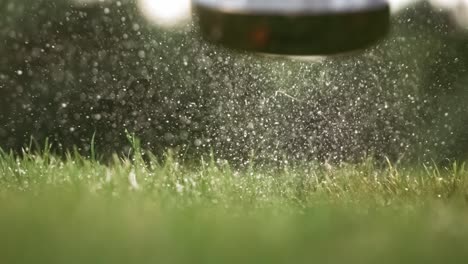 Golf-club-hits-a-golf-ball-in-a-super-slow-motion.-Drops-of-morning-dew-and-grass-particles-rise-into-the-air-after-the-impact.