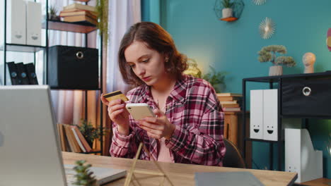 Woman-using-bank-credit-card-and-smartphone-for-online-shopping-payments-transaction-at-home-office