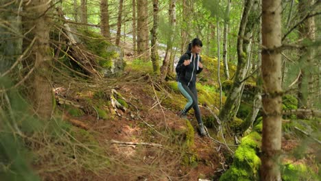 Hiking-woman-walk-with-a-hiking-backpack-in-spring-green-forest